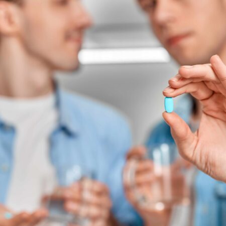Gay couple holding pre-exposure prophylaxis (PrEP) pill