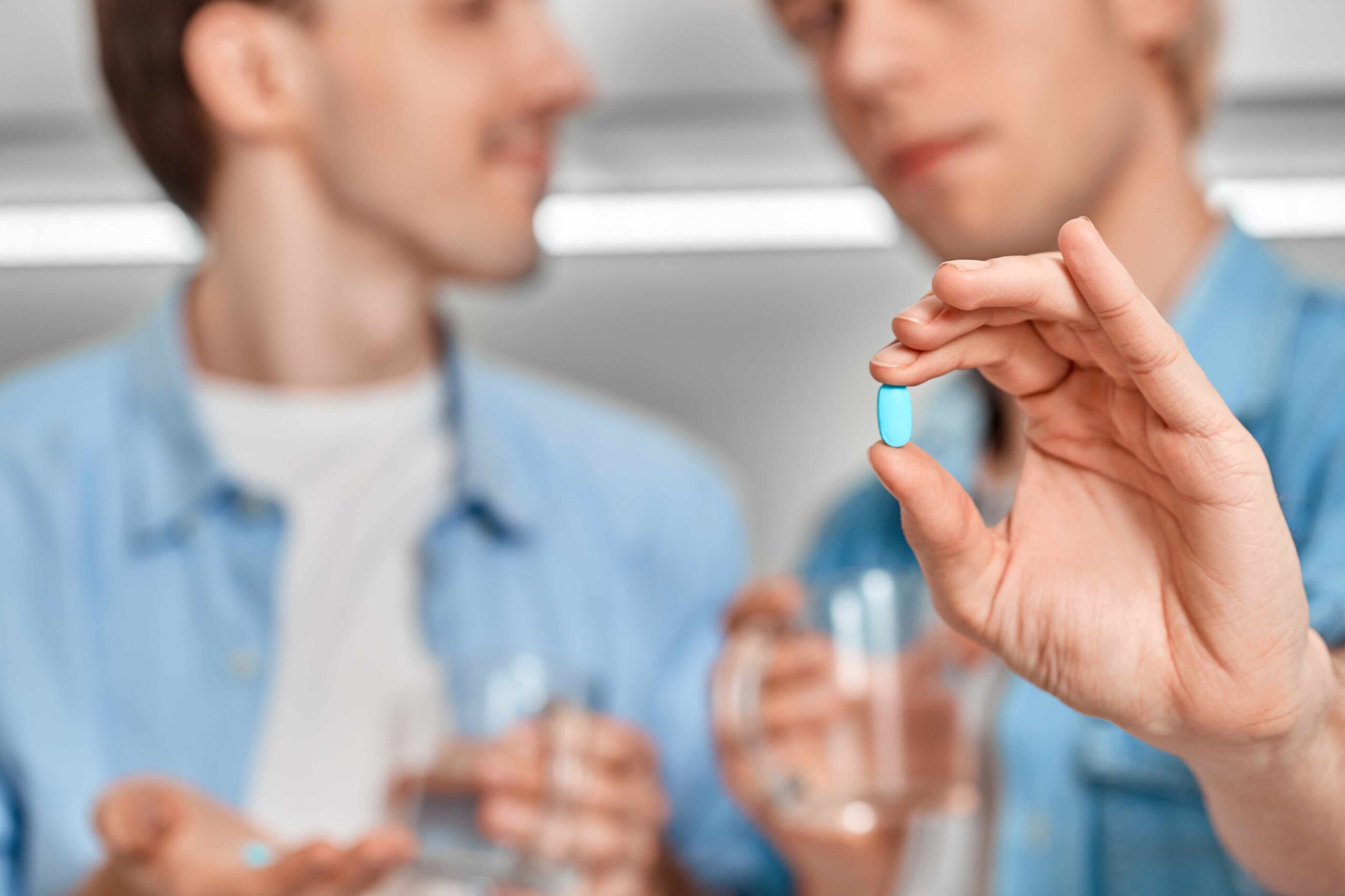 Gay couple holding pre-exposure prophylaxis (PrEP) pill